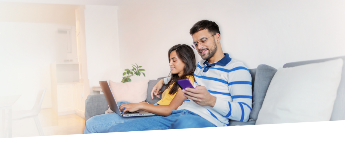 Paar sitzt gemütlich auf dem Sofa. Beide nutzen mit ihren Geräten einen günstigen DSL-Tarif von sim24.