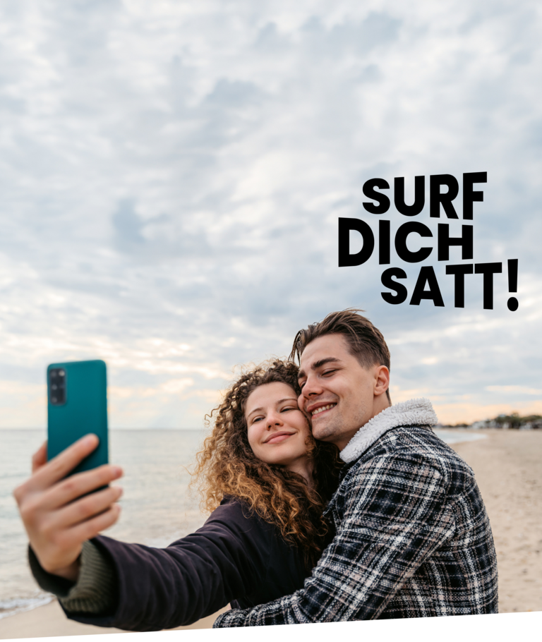 Junges Paar macht ein Selfie am Strand und nutzt einen Handytarif mit Handy