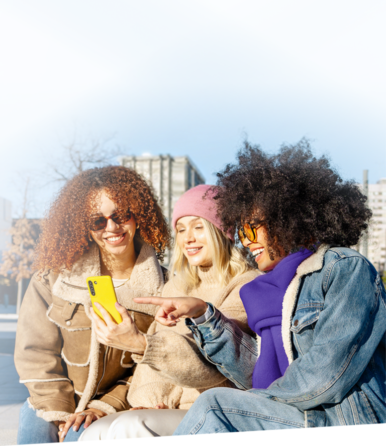 Fünf junge Erwachsene, davon zwei Huckepack halten ein Handy mit Allnet-Flat in die Höhe und machen ein fröhliches Selfie.