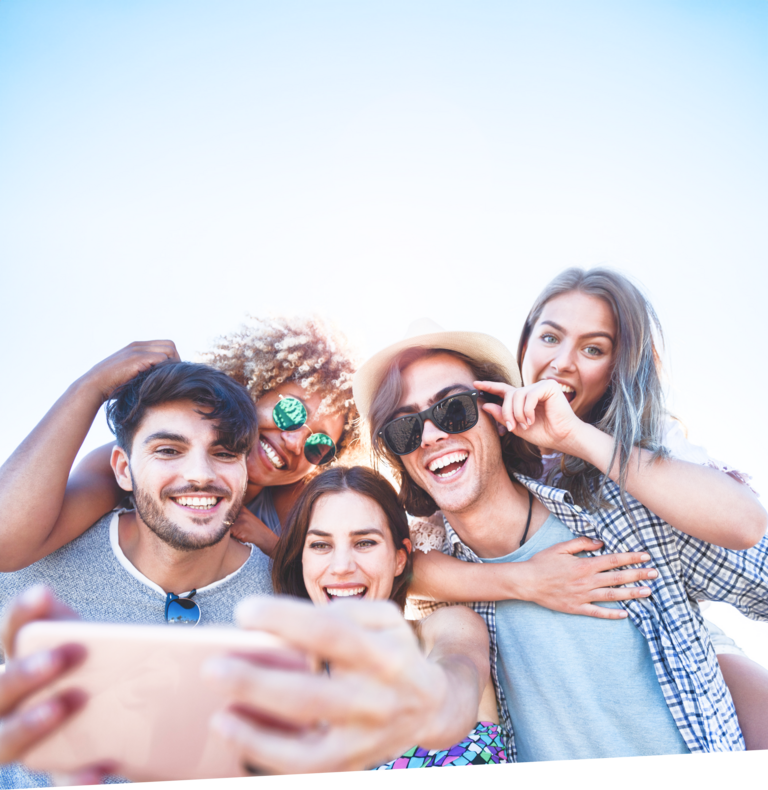 Fünf junge Erwachsene, davon zwei Huckepack halten ein Handy mit Allnet-Flat in die Höhe und machen ein fröhliches Selfie.